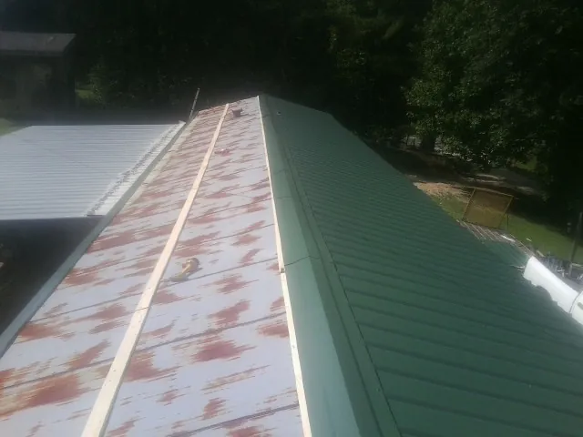 Old rusted panels beside newly installed green metal roofing in Pelican Rapids