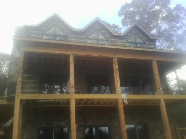Dormers and porch framing on a large log home under construction — Roof Coating work by our crew in Pelican Rapids