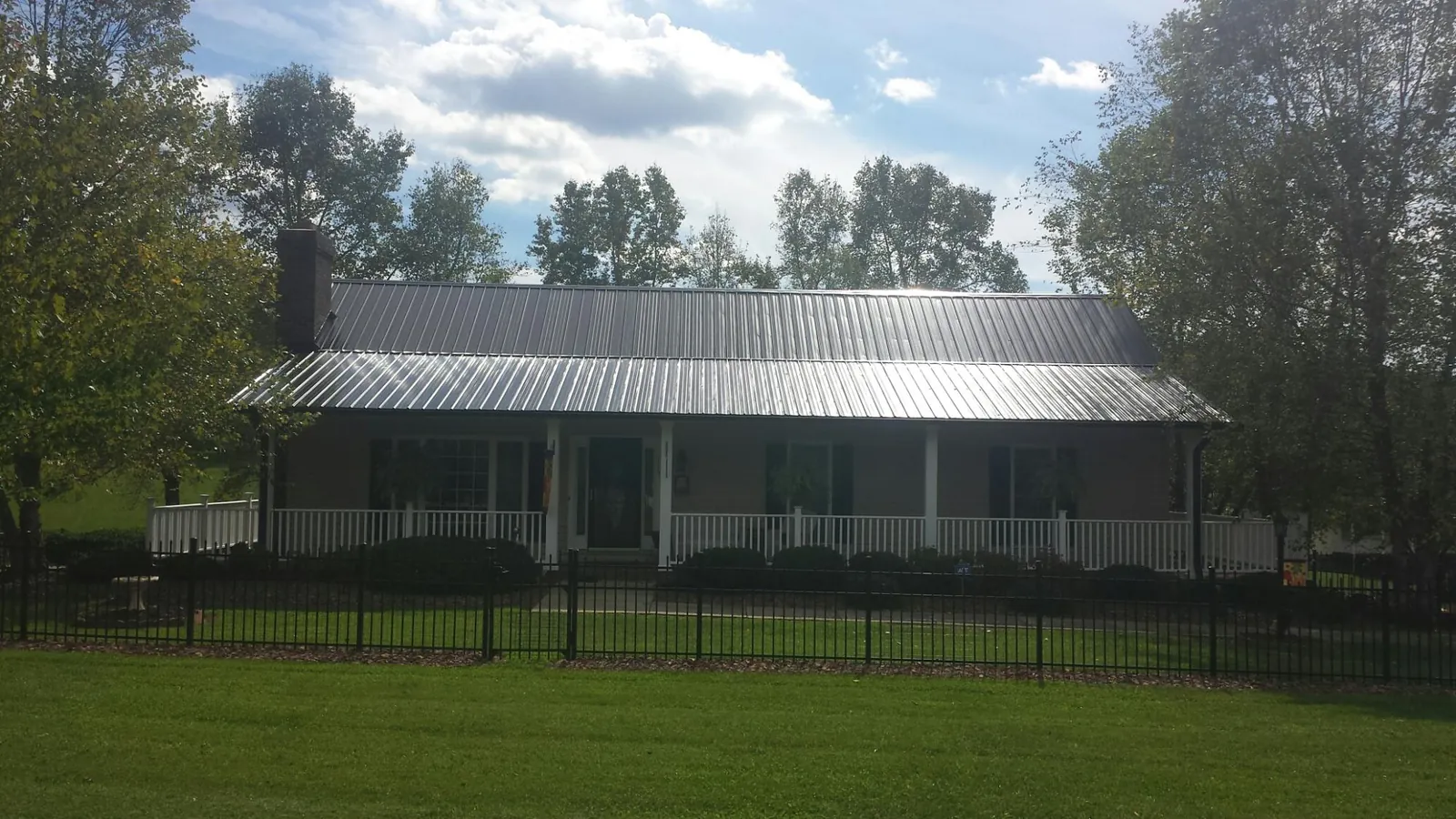 Gray metal roof on a brick ranch with a full width front porch — Gutter Guard Installation work by our crew in Pelican Rapids