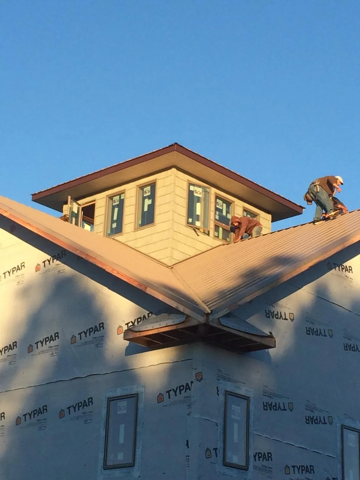 Roofers working around a rooftop cupola on a new metal roof at sunset — Roof Waterproofing in Pelican Rapids by Roofing Brothers
